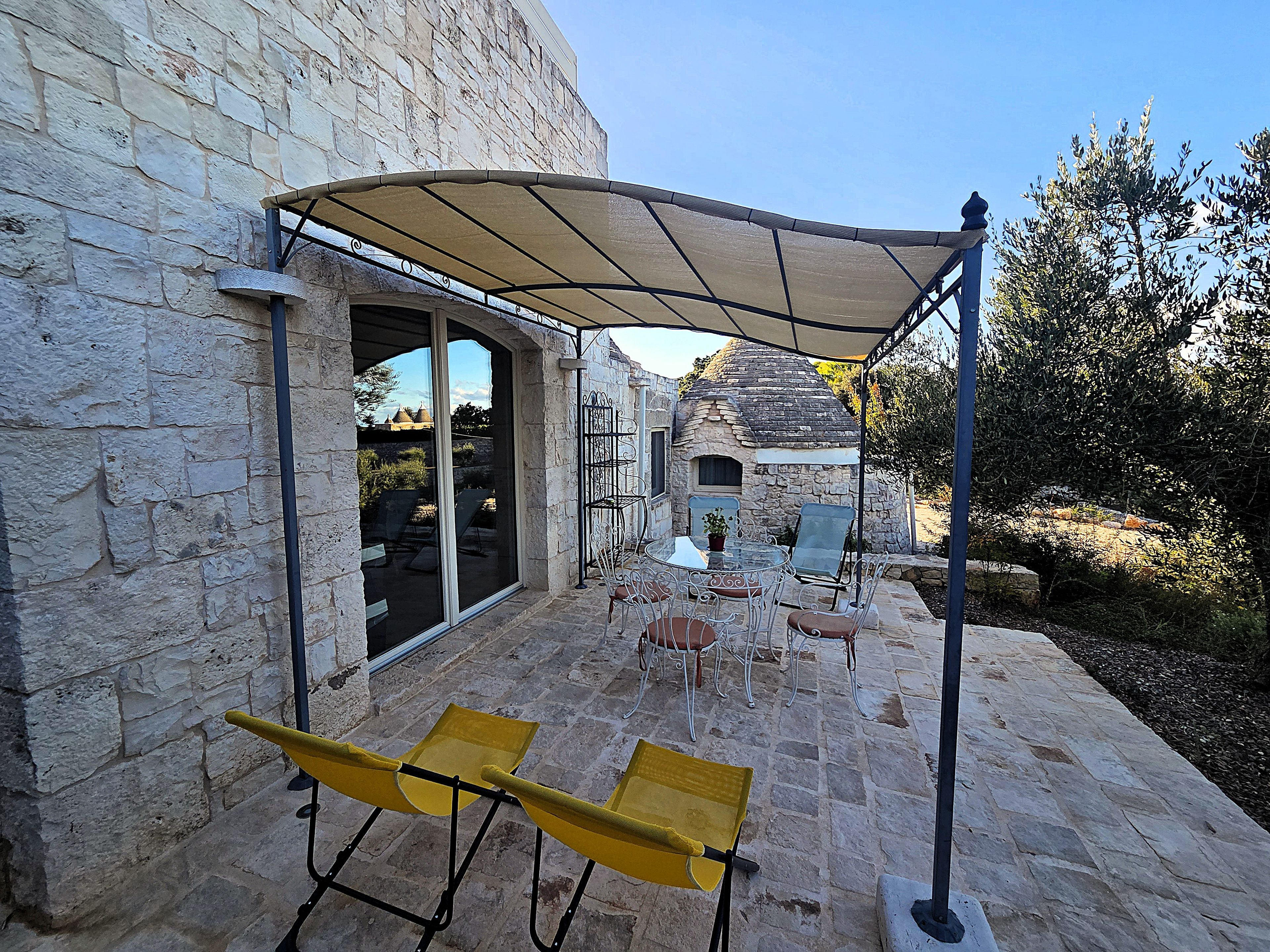 A stone building with a patio area featuring outdoor seating and a covered section.