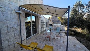 A stone building with a patio area featuring outdoor seating and a covered section.