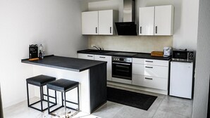 A modern kitchen with white cabinets, a black countertop, a built-in oven, a microwave, and a coffee maker.