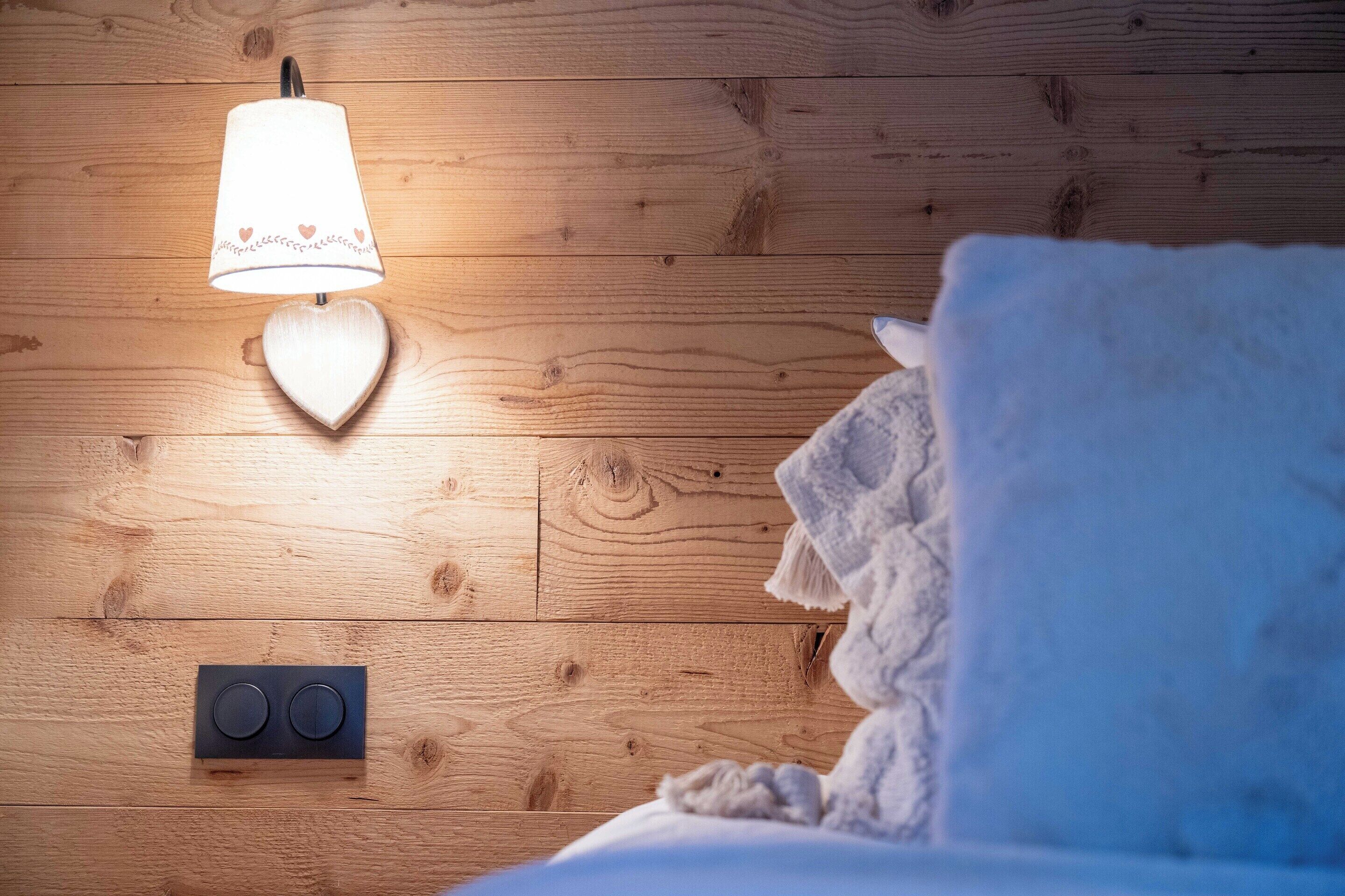 Een houten vloer met een aan de muur bevestigde lamp en een lamp met een hartvorm.