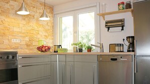 Een moderne keuken met een stenen muur, roestvrijstalen apparatuur en een raam met uitzicht.