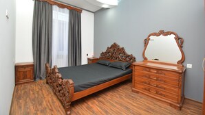 A bedroom with a wooden bed, a dresser with a mirror, and a window with curtains.