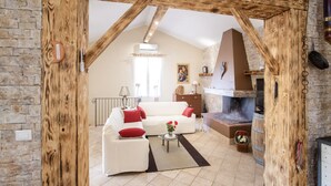 Un salon rustique avec des poutres apparentes, une cheminée et un mur en pierre.