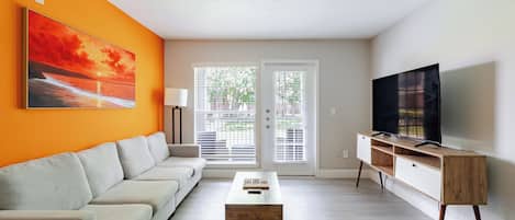 A living room with a sofa, coffee table, TV, and a painting on the wall.
