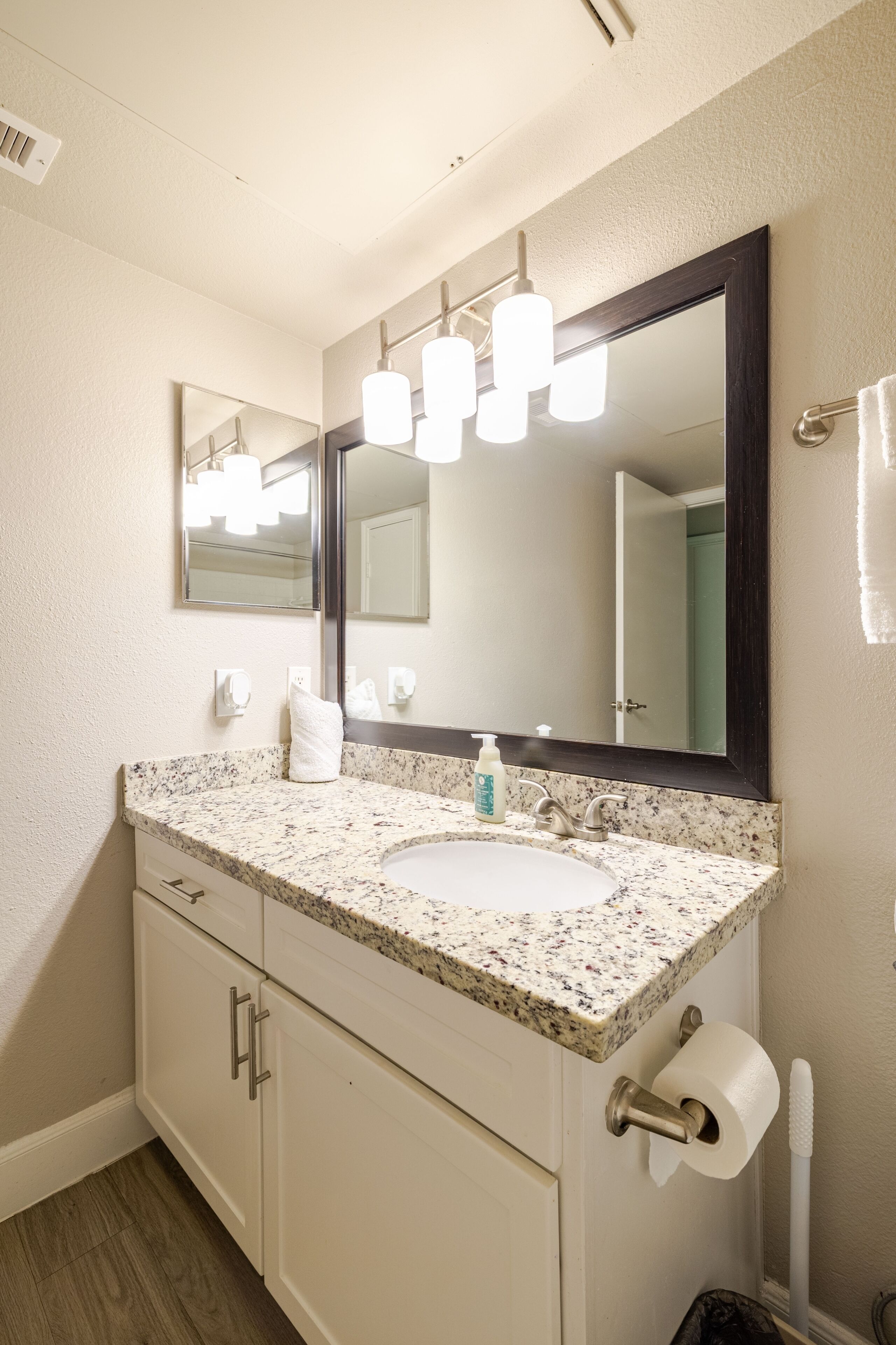 A bathroom with a white sink, a large mirror, and a towel rack.