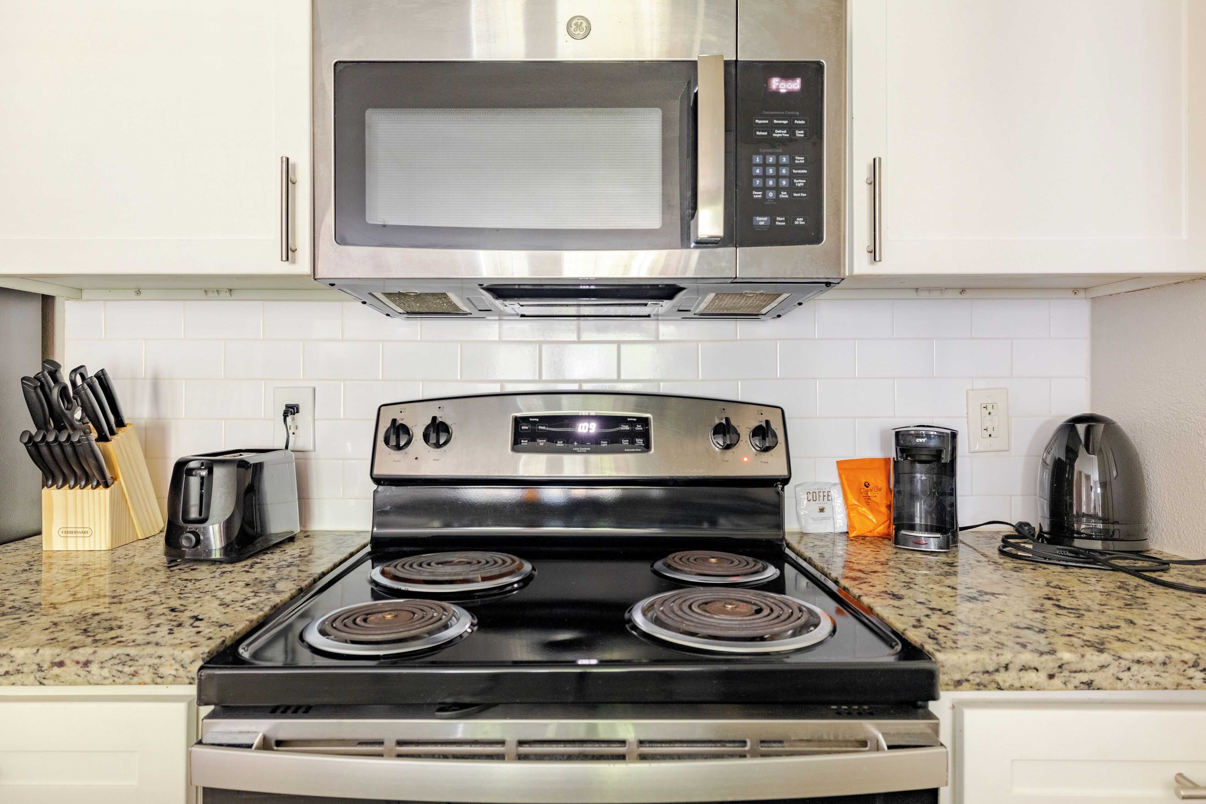 A kitchen with a stainless steel stove, a microwave, and a coffee maker.