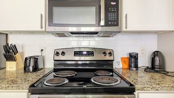 A kitchen with a stainless steel stove, a microwave, and a coffee maker.