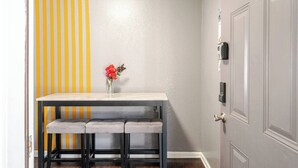 A narrow hallway with a striped wall, a small table with a vase of flowers, and a door with a lock.