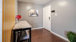 A hallway with a marble table, a bench, a door, and a painting on the wall.