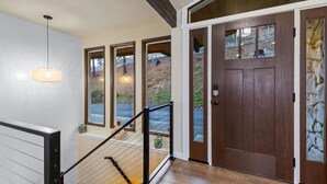 A staircase with a wooden handrail and a glass door with a stone accent. - River House with Panoramic Views (Spokane)