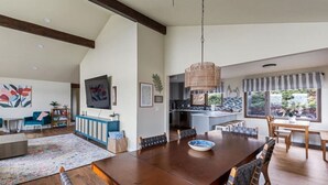 A spacious living area with a large wooden dining table, a kitchen with a modern design, and a view of the outdoors through large windows. - River House with Panoramic Views (Spokane)