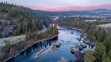A river winding through a forested valley with a road on the left and a town in the distance.