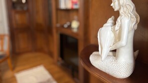 Une statue blanche représentant une femme tenant un enfant, placée sur une étagère en bois.