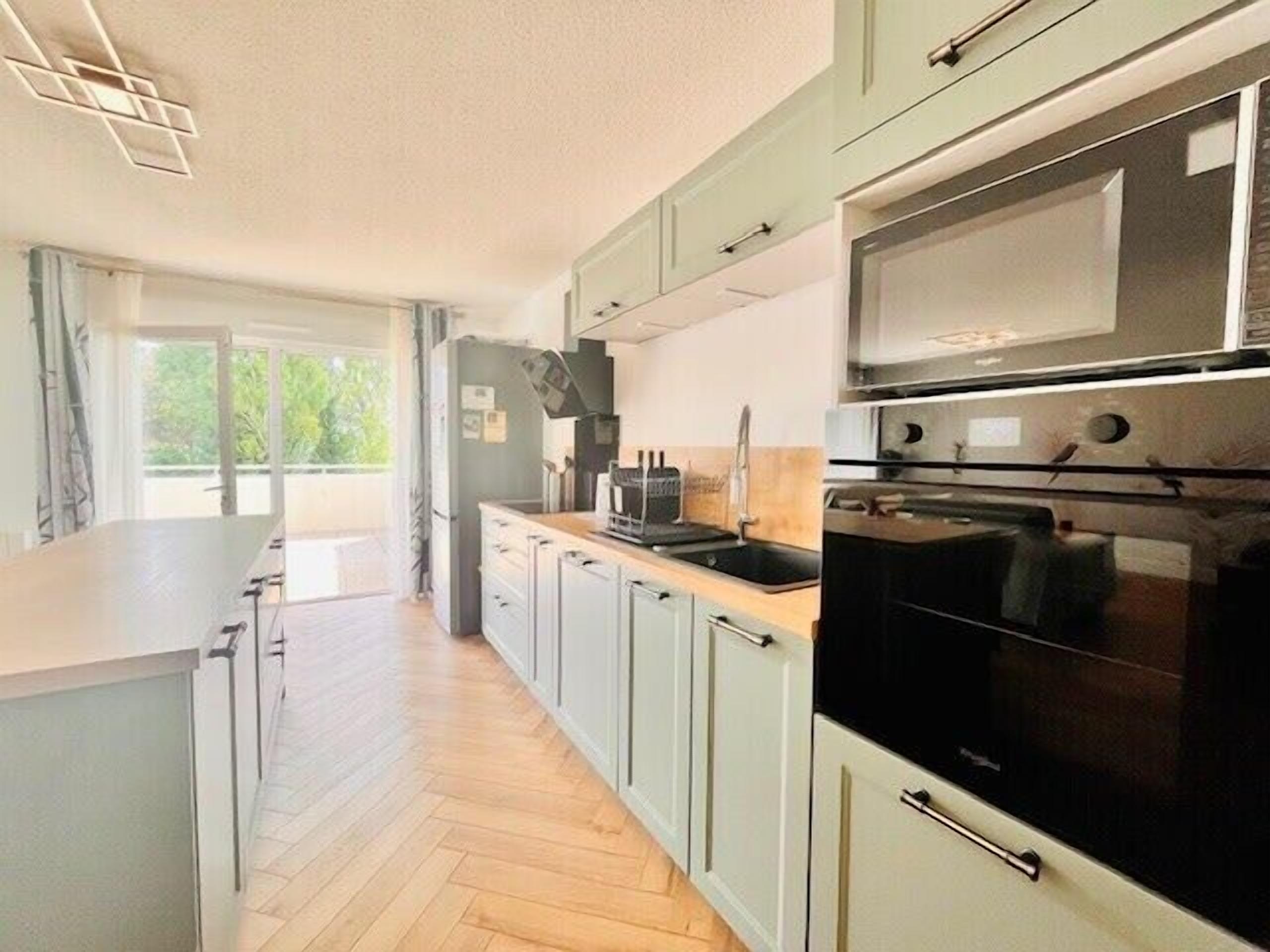 A modern kitchen with light green cabinets, a black oven, and a stainless steel microwave.