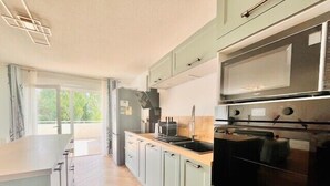 A modern kitchen with light green cabinets, a black oven, and a stainless steel microwave.