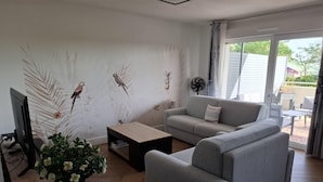 A living room with a grey sofa, a coffee table, a TV, and a wall with bird wall art.
