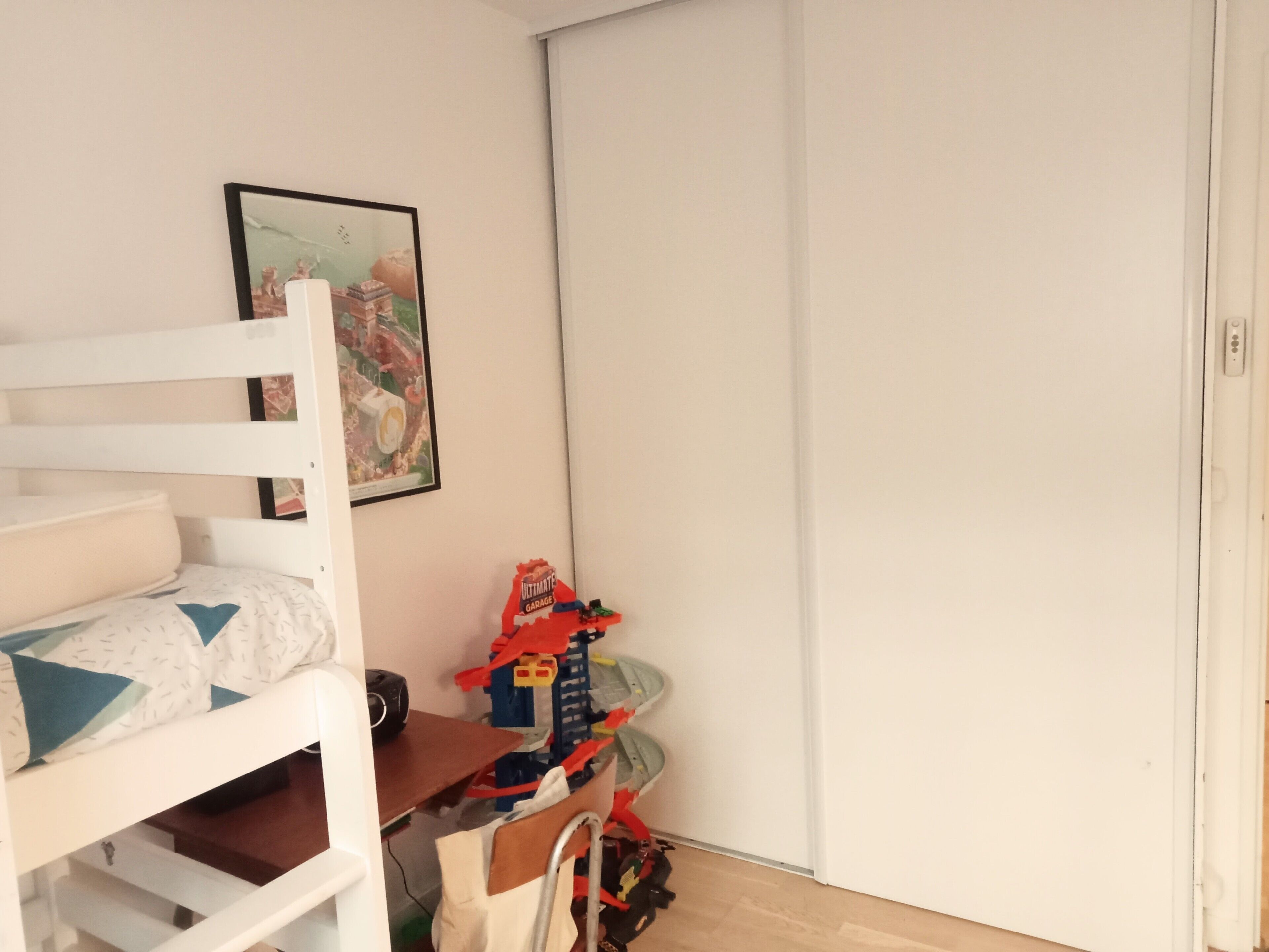 Ein Kinderstockbett mit Schreibtisch und Stuhl, ein Spielzeugauto und ein gerahmtes Bild an der Wand.