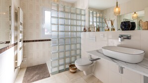 A modern bathroom with a glass partition, a white sink, and a large mirror.