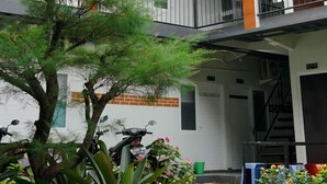 A multi-story building with air conditioning units, balconies, and a tree in the courtyard. - Puspiptek Residence Syariah (South Tangerang)