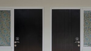 Two dark wooden doors with a white frame and a logo on the right door. - Puspiptek Residence Syariah (South Tangerang)