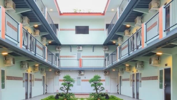 A hotel atrium with a central garden, hexagonal patterned floor, and multiple balconies. - Puspiptek Residence Syariah (South Tangerang)