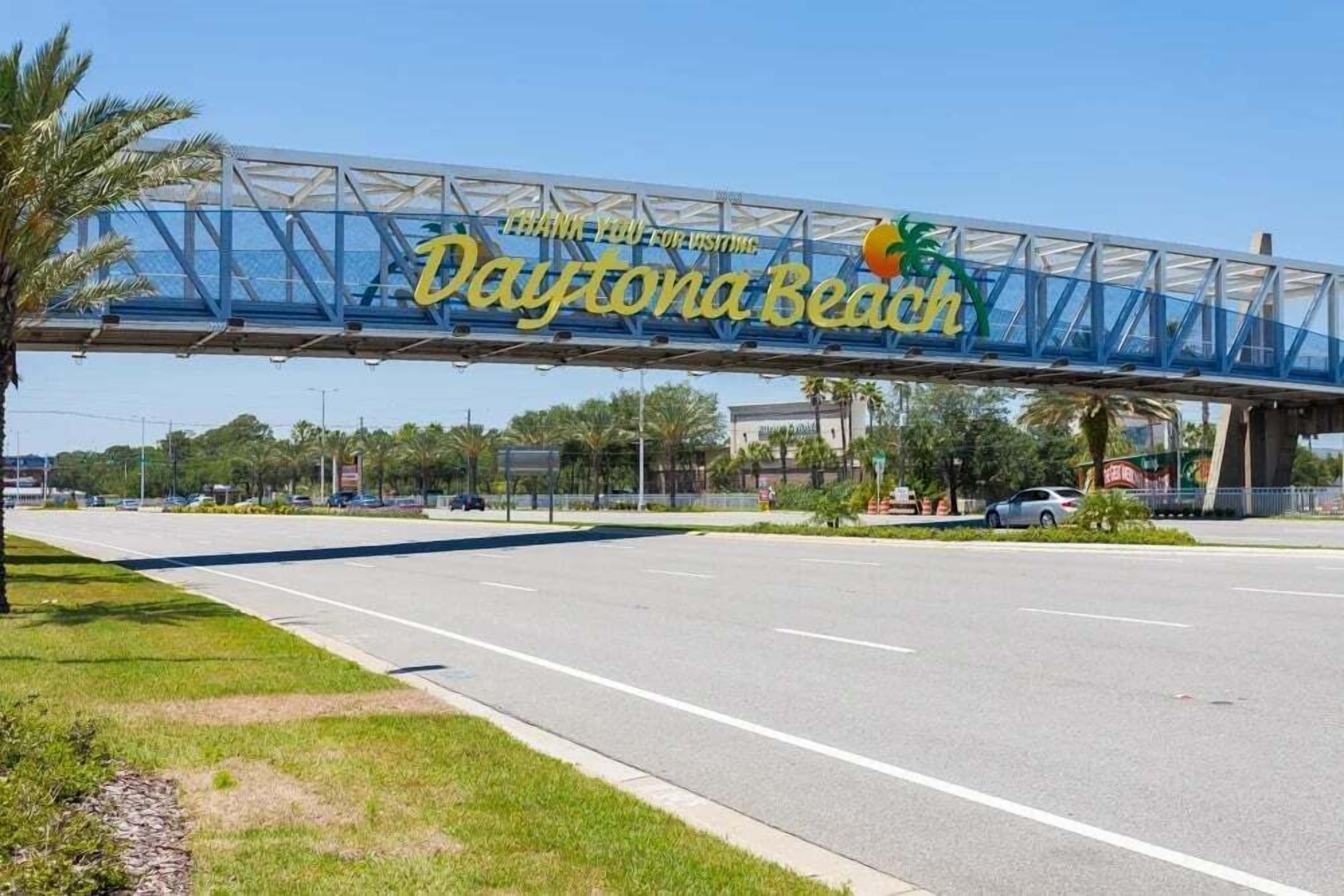 Une enseigne en forme de pont portant l’inscription « Merci de votre visite à Daytona Beach » et ornée d’un logo représentant un palmier.