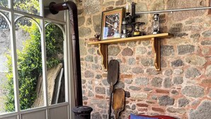 A cozy room with a stone wall, a wooden table, a red sofa, and a vintage stove.