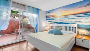 A bedroom with a bed, a nightstand, a window with curtains, and a view of the ocean. - Holiday Home 'Deti' with Private Terrace and Wi-Fi (Roses)