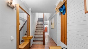 A narrow hallway with a wooden staircase, a small wooden bench, and a metal rack. - Holiday Home 'Deti' with Private Terrace and Wi-Fi (Roses)