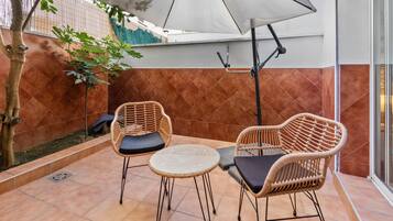 A patio with two wicker chairs, a small round table, and a white umbrella.