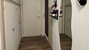 Un couloir avec un plancher en bois, une porte blanche et un miroir accroché au mur.