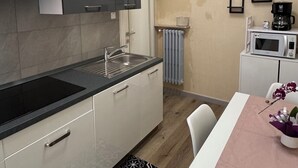 Une cuisine de taille réduite avec un plan de travail noir, des placards blancs et un four à micro-ondes.