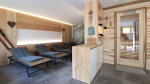 Un espacio de spa de madera con dos sillones reclinables, un mostrador de recepción y un letrero que indica sauna.