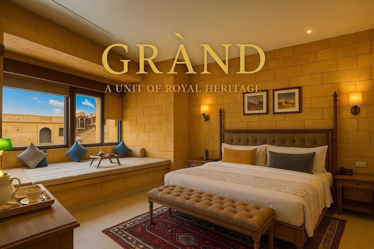 Quarto de hotel com uma cama grande, um banco, uma janela com vista para um edifício histórico e uma luminária fixada na parede.