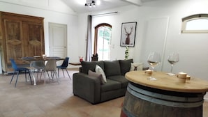 Un salon spacieux comprenant un coin repas, une table en forme de tonneau en bois et une grande fenêtre ornée d’une image de cerf.