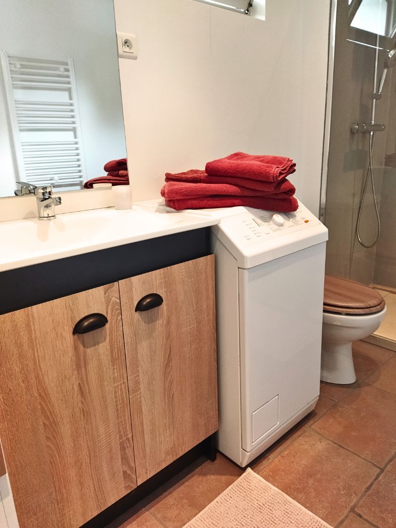 Une salle de bain moderne avec un meuble-lavabo en bois, des toilettes blanches et une cabine de douche en verre.