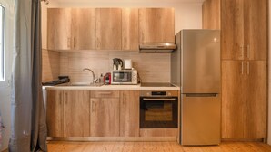 A modern kitchen with wooden cabinets, a stainless steel refrigerator, a microwave, and an oven. - Joseph's Studio by Corfuescapes (Corfu)
