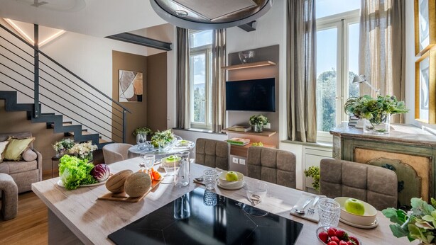 A modern living room with a dining area, a staircase, and a large window with a view. - Verdi 1928, A Cozy Wallside Retreat (Lucca)