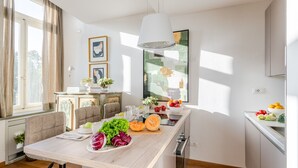A modern kitchen with a central island, wooden cabinets, and a large window providing natural light. - Verdi 1928, A Cozy Wallside Retreat (Lucca)