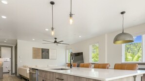 Una cucina moderna con una grande isola, illuminazione a sospensione e ventilatore a soffitto.