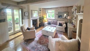 Un salon spacieux avec une cheminée, des meubles blancs et un mur en pierre.
