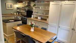 Une cuisine avec une table en bois, des chaises, un fourneau et des placards.