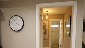 A hallway with a clock, a light fixture, and a door leading to a bathroom. - Eclectic Charm (Douglasville)