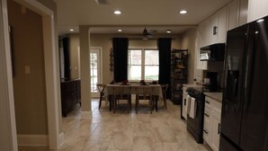 A spacious kitchen with a dining area, featuring a large refrigerator, oven, and a dining table set for four. - Eclectic Charm (Douglasville)