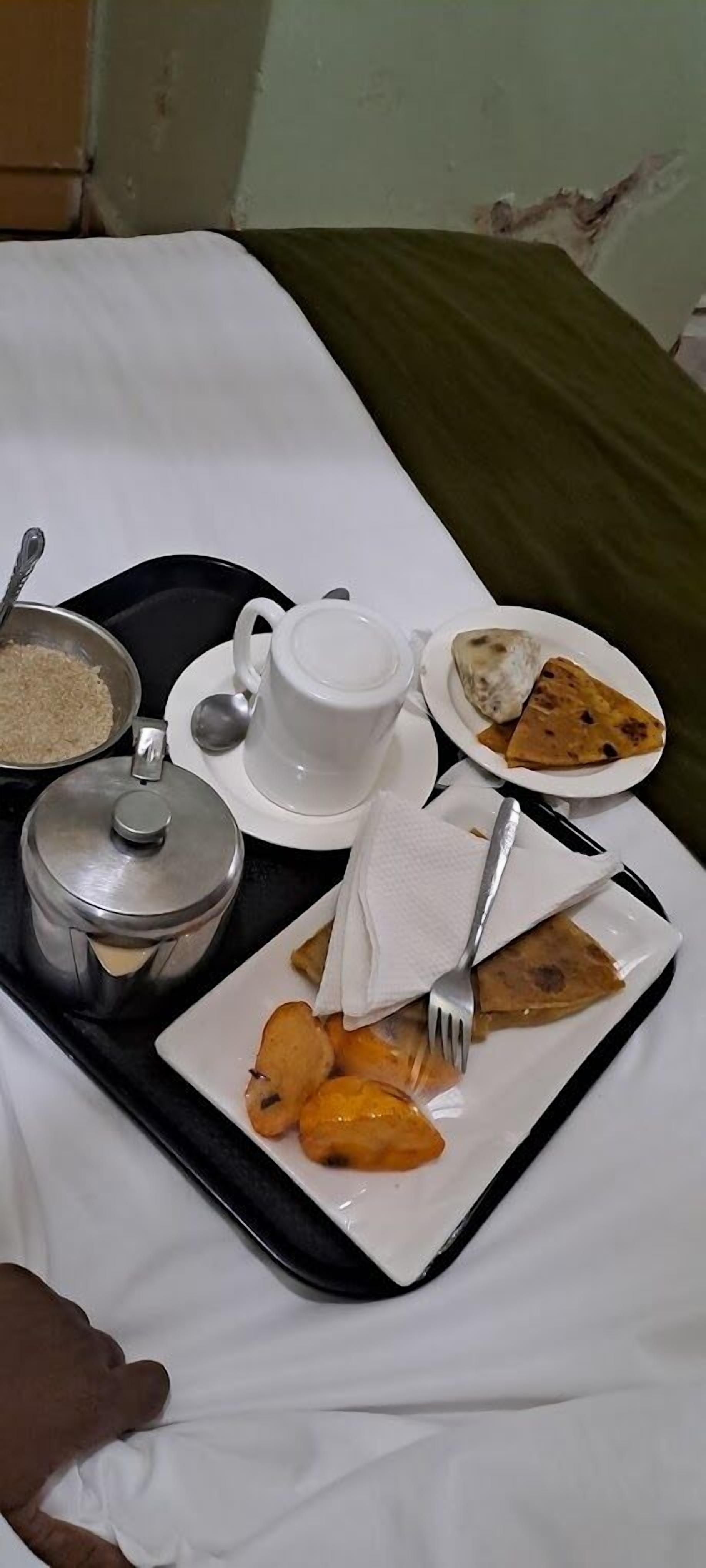 Una bandeja con alimentos, incluyendo arroz, una taza, un plato con un pastel y un plato con masa frita.