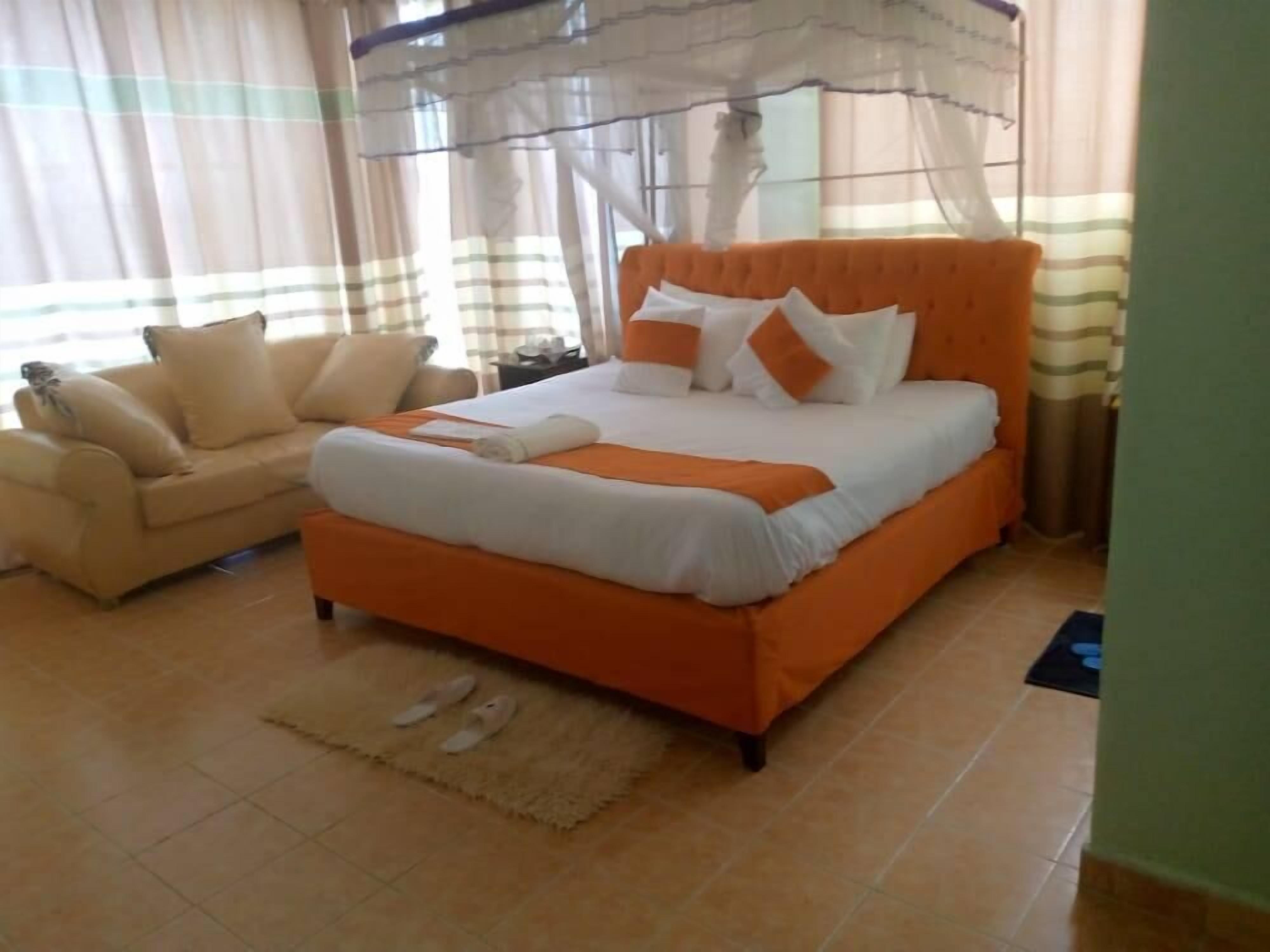 Une chambre à coucher avec un lit, un canapé et une fenêtre avec des rideaux.