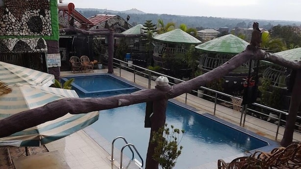 Un espace piscine sur le toit, offrant une vue sur les collines lointaines, avec un toboggan et des sièges extérieurs.