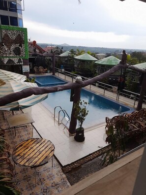 Área de piscina en la azotea con vistas a colinas distantes, un tobogán y mobiliario exterior.