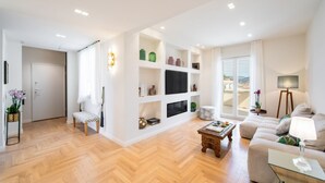 A modern living room with a sofa, a coffee table, and a TV mounted on the wall. There is a door leading to another room and a window with a view. - New Luxury Penthouse 2 steps from downtown (Firenze)