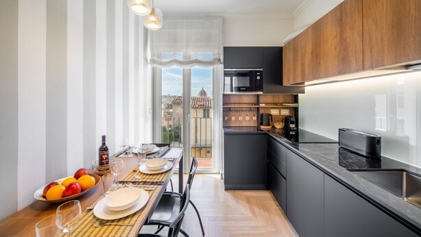 A modern kitchen with a dining area, a view through a glass door, and a dining table set with plates and glasses. - New Luxury Penthouse 2 steps from downtown (Firenze)